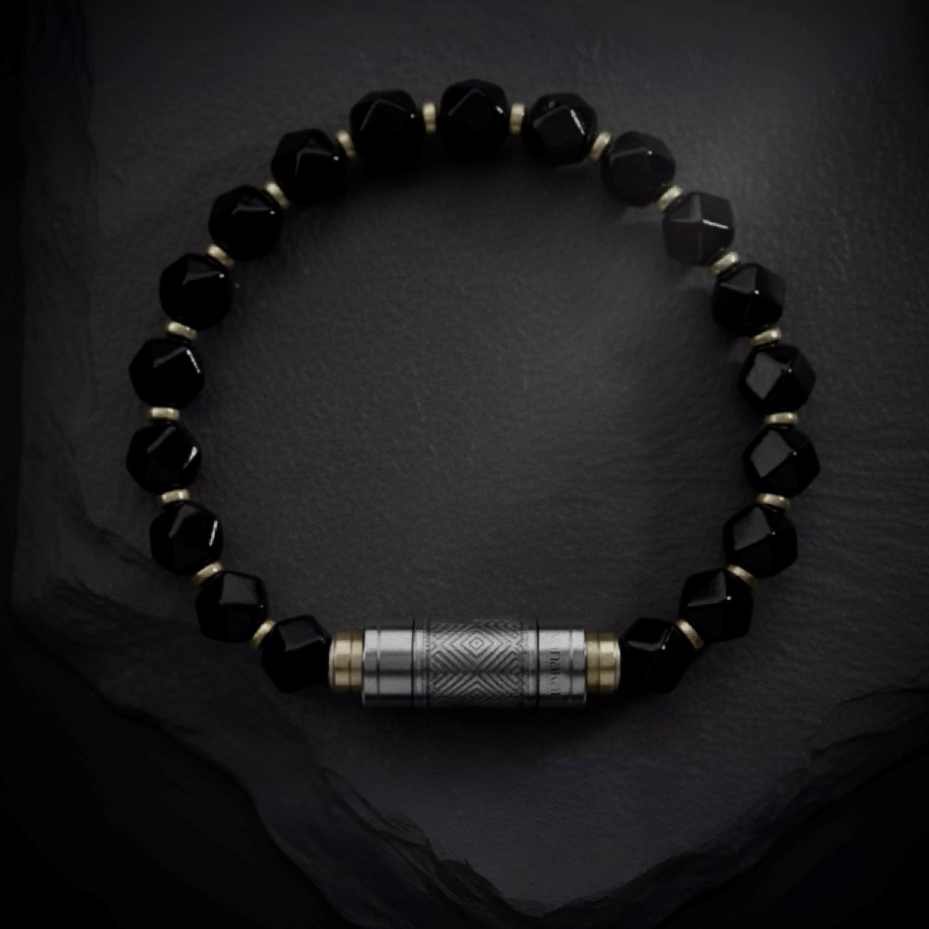 O-Punch Silver Edition – top view, faceted obsidian beads with gold spacers and silver engraved punch tool on dark stone