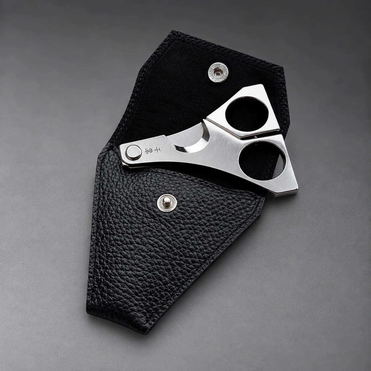 FUJI leather case – open with scissors, angled view showing sculpted form and grained cowhide texture