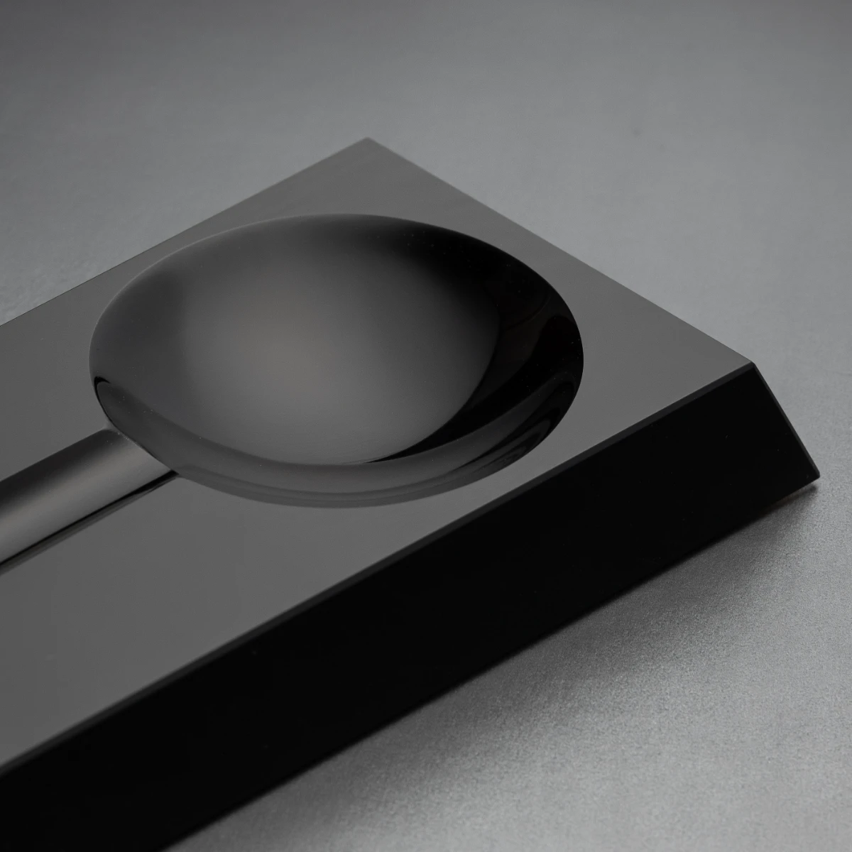 Loupe ashtray — bevelled obsidian exterior, top view